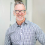 Homme souriant avec des lunettes et une chemise à carreaux