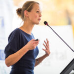 Femme faisant une présentation devant un micro.