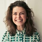 Femme souriante aux cheveux bouclés portant une chemise à motifs