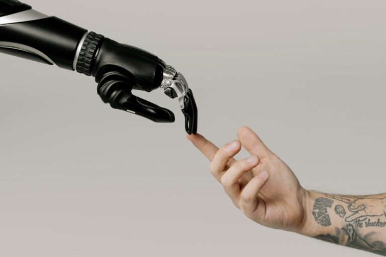 Une main humaine tatouée touche délicatement le doigt d’une main robotique noire et métallique, symbolisant l’interaction entre l’intelligence artificielle et l’humanité.